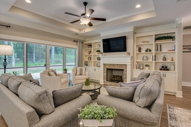 living room with a fireplace, hardwood / wood-style floors, a raised ceiling, and ceiling fan