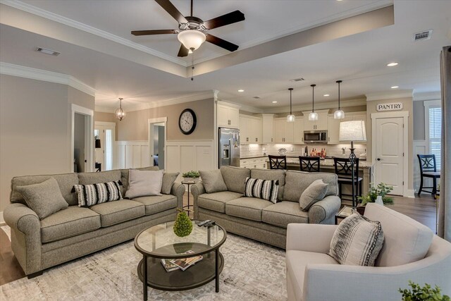 living room featuring ceiling fan with notable chandelier, crown molding, and light hardwood / wood-style flooring