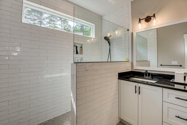 bathroom with tiled shower, vanity, and tile walls