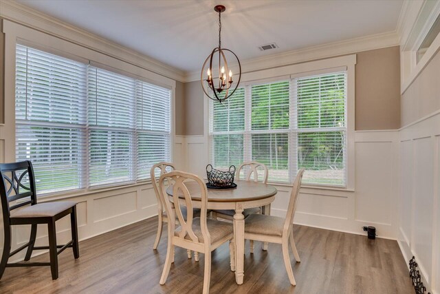 dining room featuring hardwood / wood-style flooring, crown molding, and an inviting chandelier