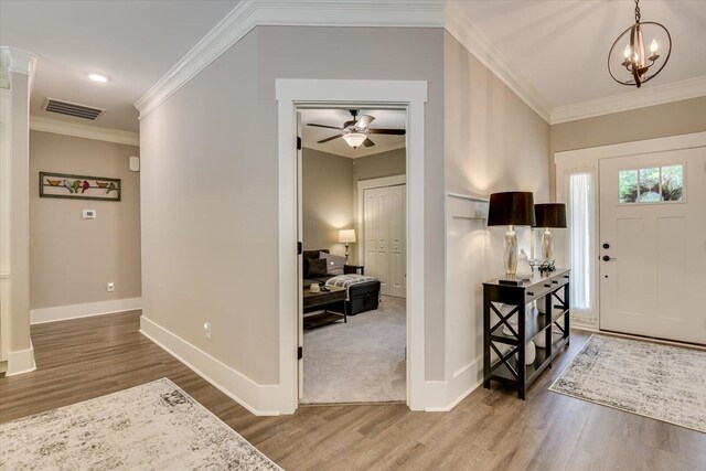 entryway with hardwood / wood-style floors, ceiling fan with notable chandelier, and ornamental molding