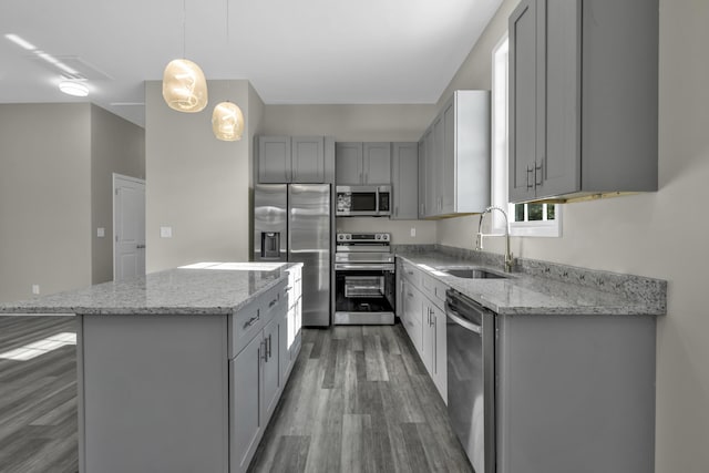 kitchen with gray cabinetry, stainless steel appliances, sink, pendant lighting, and a center island