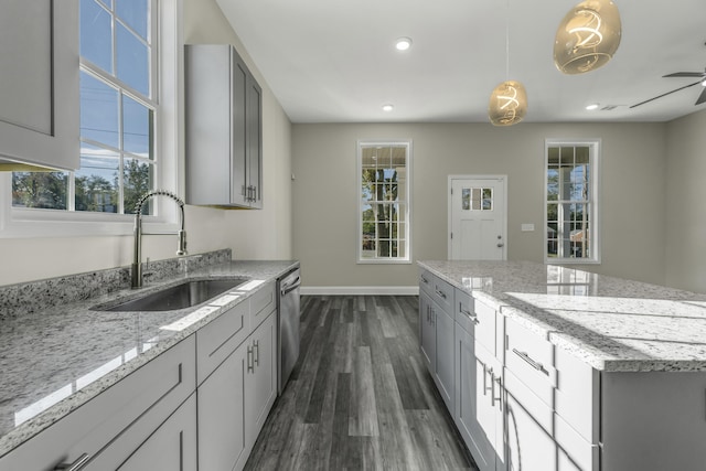 kitchen with light stone countertops, stainless steel dishwasher, gray cabinetry, sink, and hanging light fixtures