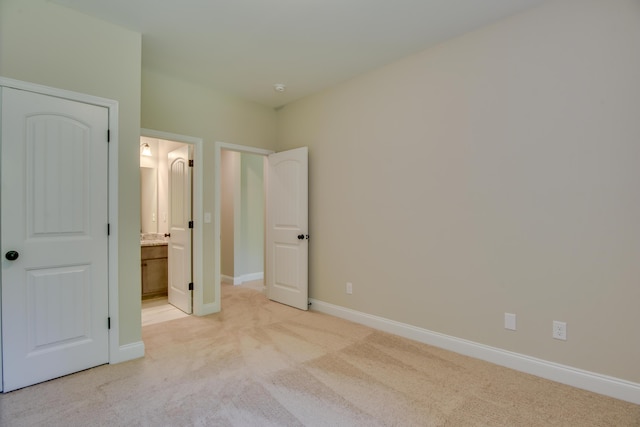 unfurnished bedroom featuring light colored carpet and ensuite bath