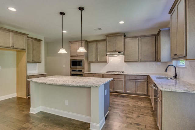 kitchen with light stone countertops, sink, dark hardwood / wood-style floors, a kitchen island, and appliances with stainless steel finishes