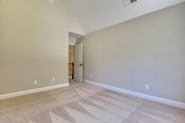 spare room featuring light colored carpet and high vaulted ceiling