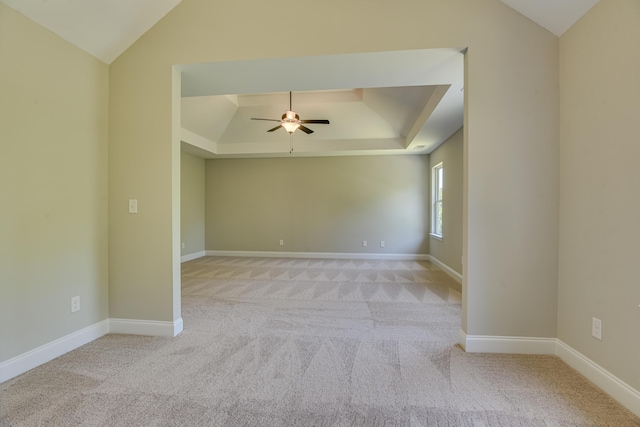 carpeted empty room featuring a raised ceiling, ceiling fan, and vaulted ceiling