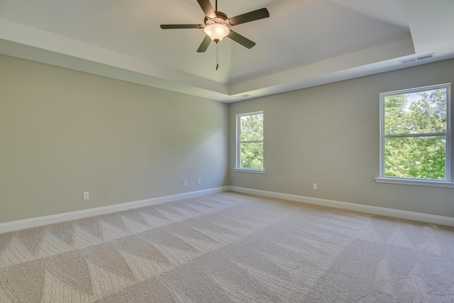 carpeted empty room featuring a raised ceiling and ceiling fan