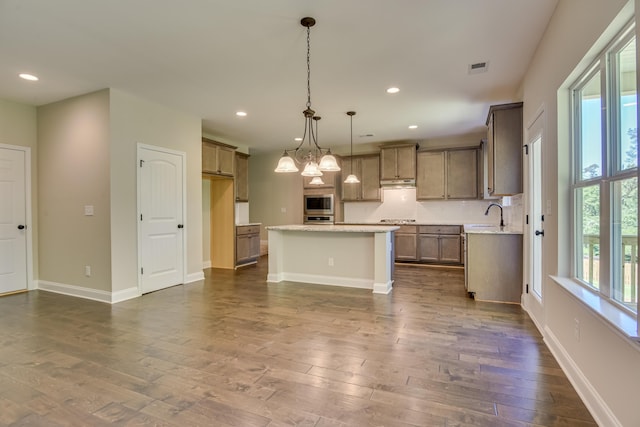 kitchen featuring dark hardwood / wood-style flooring, decorative light fixtures, a notable chandelier, a kitchen island, and stainless steel microwave