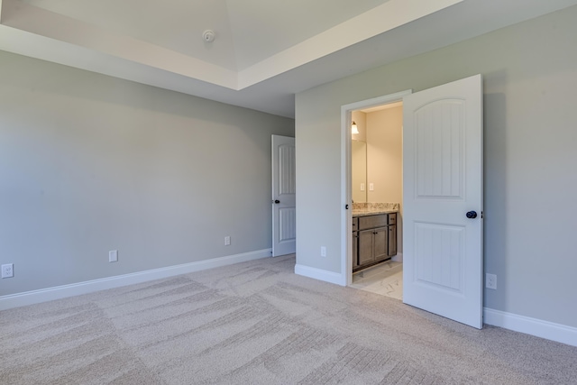 unfurnished bedroom with ensuite bath, light carpet, and vaulted ceiling