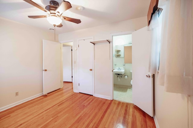 unfurnished bedroom featuring sink, ensuite bath, ceiling fan, and light wood-type flooring