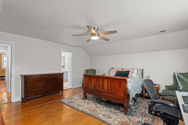 bedroom with wood-type flooring, a textured ceiling, baseboards, vaulted ceiling, and a ceiling fan