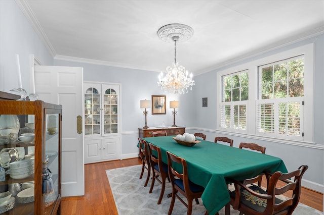 dining area with a chandelier, wood finished floors, and ornamental molding