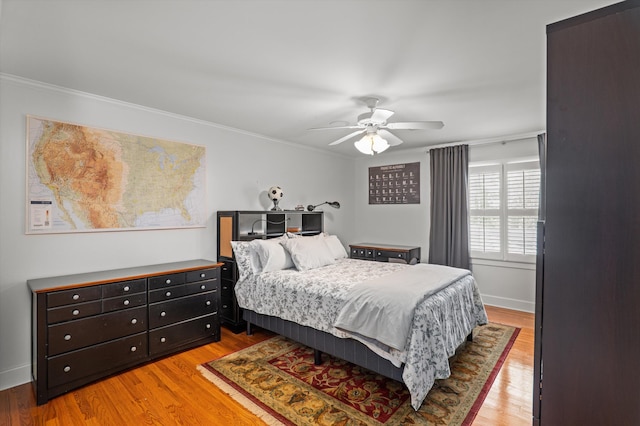 bedroom with ornamental molding, light wood-style floors, baseboards, and ceiling fan