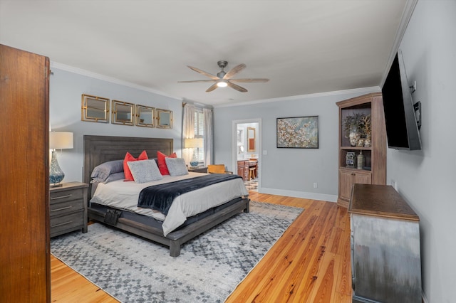 bedroom featuring crown molding, wood finished floors, baseboards, ensuite bath, and a ceiling fan