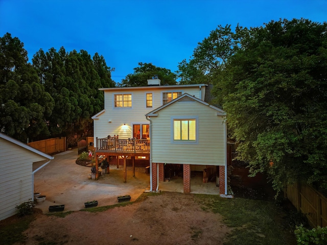 back of house with a carport, a wooden deck, a fenced backyard, and a patio