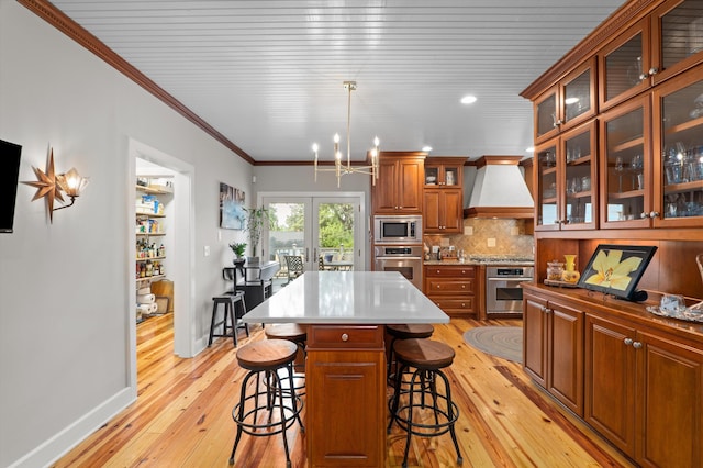 kitchen featuring appliances with stainless steel finishes, custom exhaust hood, light wood-style floors, brown cabinetry, and ornamental molding