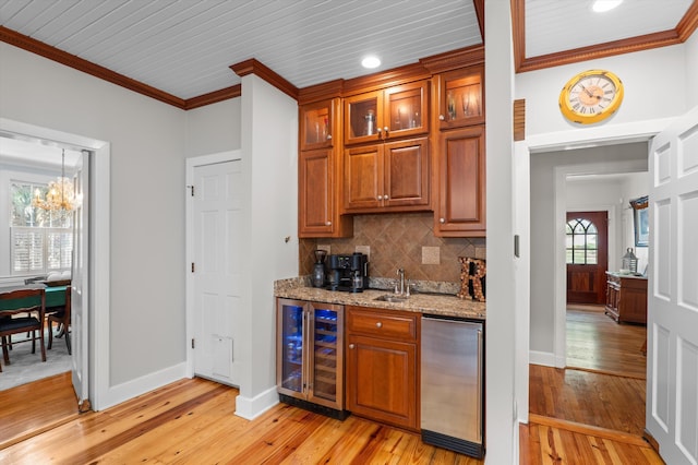 kitchen featuring beverage cooler, a sink, ornamental molding, light wood-type flooring, and backsplash