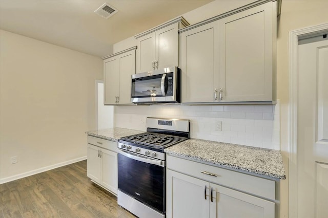 kitchen featuring light stone counters, wood-type flooring, appliances with stainless steel finishes, and tasteful backsplash