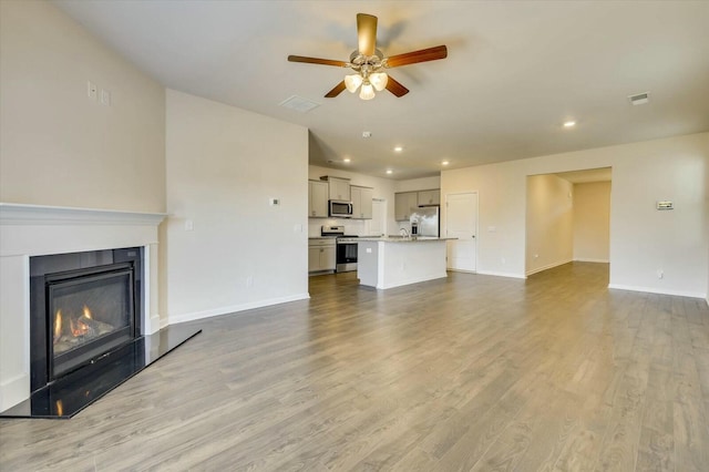 unfurnished living room featuring ceiling fan and light hardwood / wood-style flooring