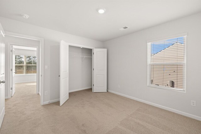 unfurnished bedroom featuring light colored carpet and a closet