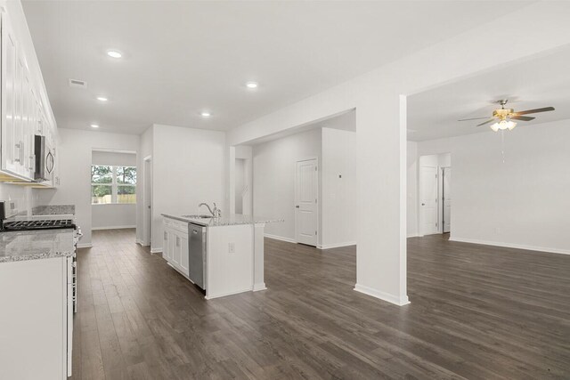 kitchen with white cabinets, a center island with sink, sink, stainless steel dishwasher, and light stone countertops