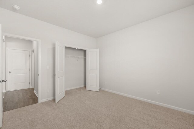 unfurnished bedroom with light carpet and a closet