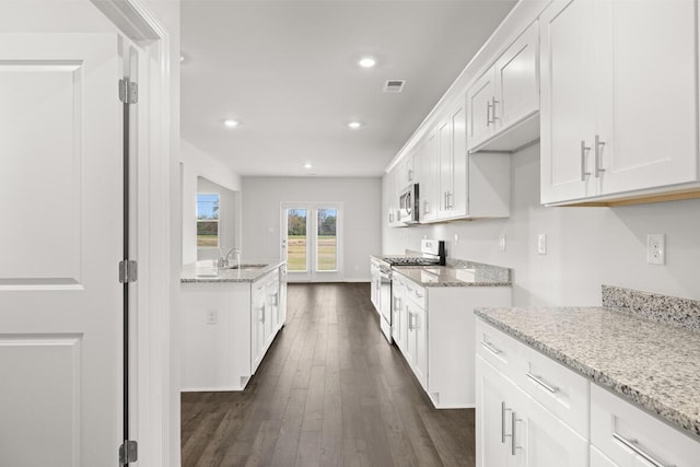 kitchen featuring appliances with stainless steel finishes, dark hardwood / wood-style flooring, light stone counters, sink, and white cabinetry