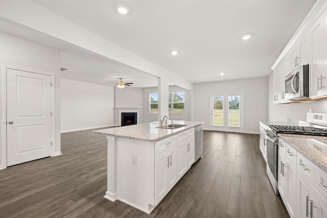 kitchen featuring a kitchen island with sink, white cabinets, sink, appliances with stainless steel finishes, and light stone counters