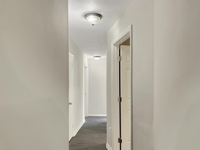 hallway with dark hardwood / wood-style flooring and a textured ceiling