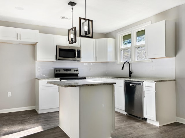 kitchen with white cabinets, sink, decorative light fixtures, a kitchen island, and stainless steel appliances