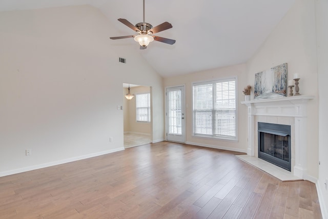 unfurnished living room with a tiled fireplace, light hardwood / wood-style flooring, high vaulted ceiling, and ceiling fan