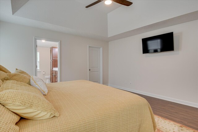 bedroom with a ceiling fan, vaulted ceiling, wood finished floors, baseboards, and connected bathroom