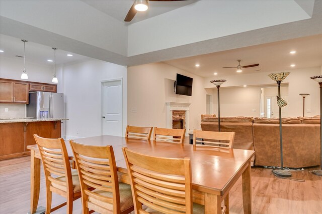 dining area featuring recessed lighting, ceiling fan, a stone fireplace, and light wood-style floors