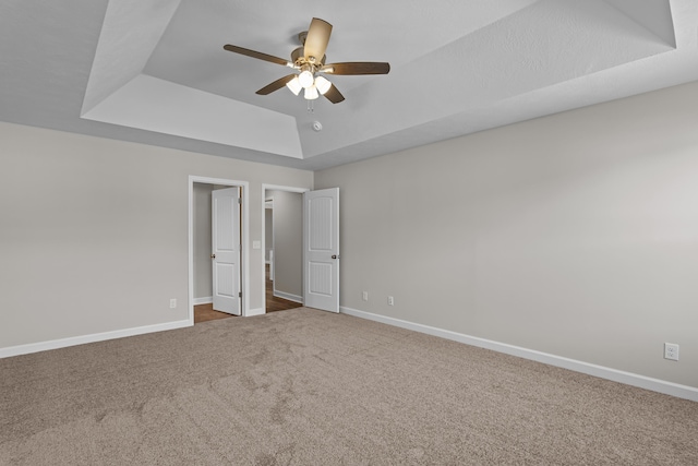 unfurnished bedroom featuring carpet floors, ceiling fan, and a tray ceiling