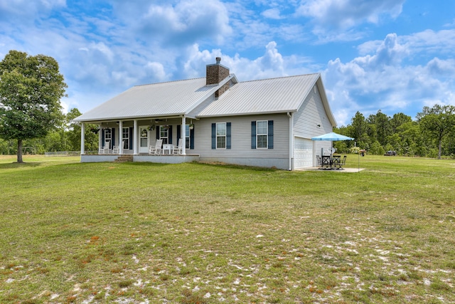 rear view of property with a garage, a lawn, and covered porch