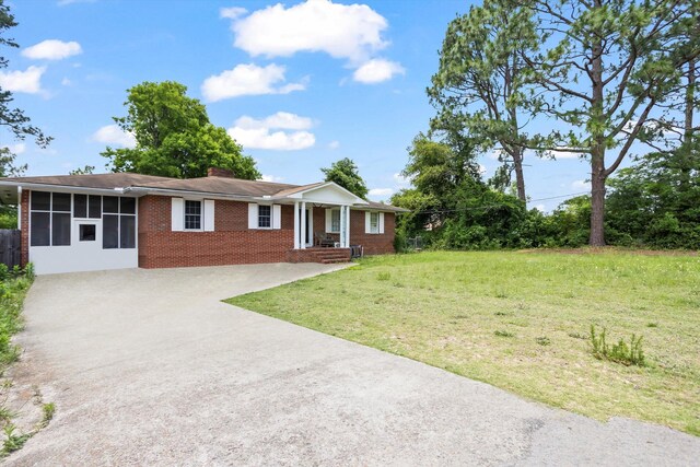 102 Briarcliff St, Belvedere, SC 29841 - ranch-style home featuring brick siding, concrete driveway, a chimney, a front yard, and a sunroom