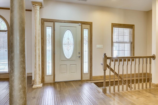 entrance foyer with decorative columns, wood finished floors, and a wealth of natural light