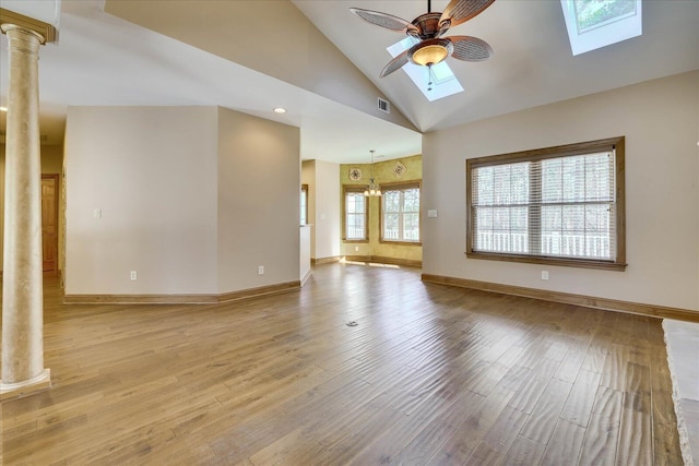 unfurnished living room with baseboards, ceiling fan, light wood-style flooring, a skylight, and ornate columns