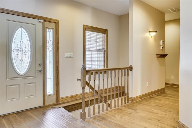 foyer entrance with wood finished floors, visible vents, and baseboards