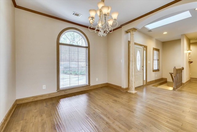 unfurnished room featuring a healthy amount of sunlight, visible vents, ornate columns, and light wood-type flooring