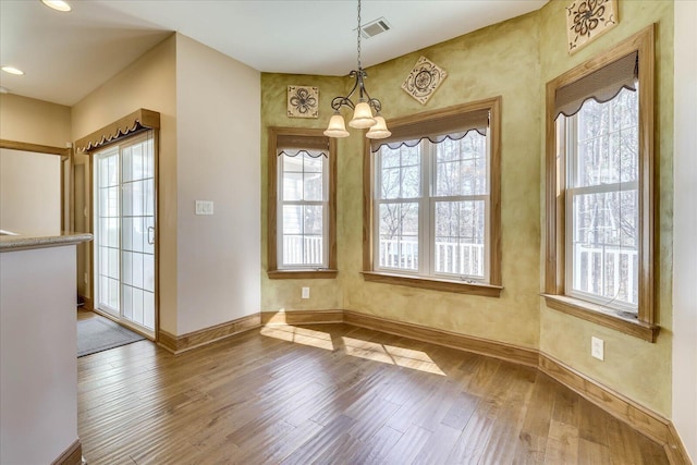 unfurnished dining area with wood finished floors, visible vents, baseboards, an inviting chandelier, and recessed lighting