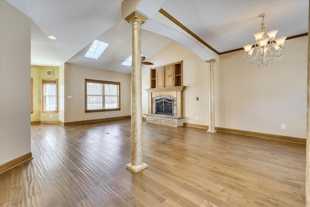 unfurnished living room featuring light wood finished floors, a brick fireplace, baseboards, lofted ceiling, and ornate columns