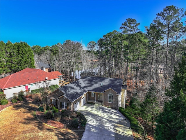 view of front facade with driveway, a forest view, and a garage