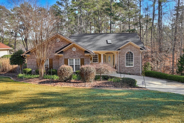 view of front facade featuring brick siding, concrete driveway, a front yard, and a shingled roof