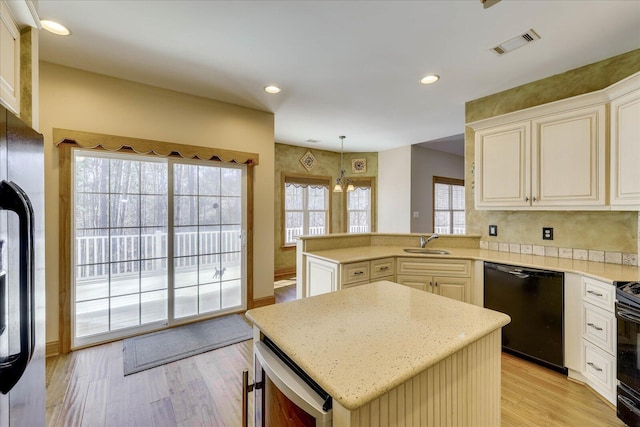 kitchen featuring visible vents, black appliances, beverage cooler, a sink, and light wood-style floors