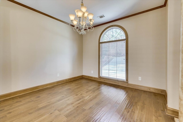 unfurnished room with visible vents, a notable chandelier, ornamental molding, wood finished floors, and baseboards