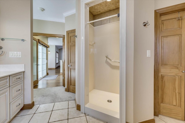 bathroom with a stall shower, ornamental molding, tile patterned flooring, baseboards, and vanity