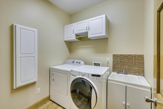 washroom featuring separate washer and dryer, cabinet space, light wood-type flooring, and a sink