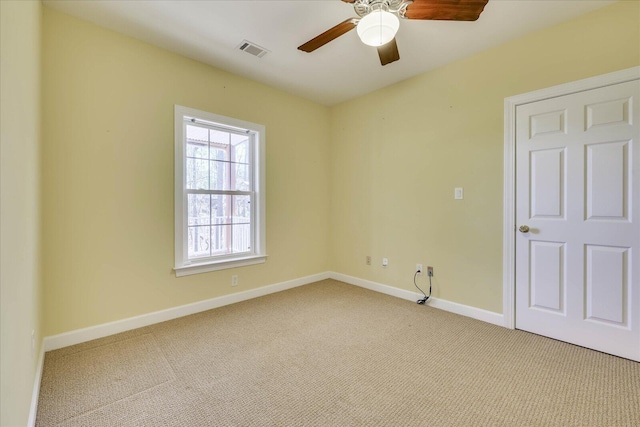 carpeted spare room featuring visible vents, ceiling fan, and baseboards